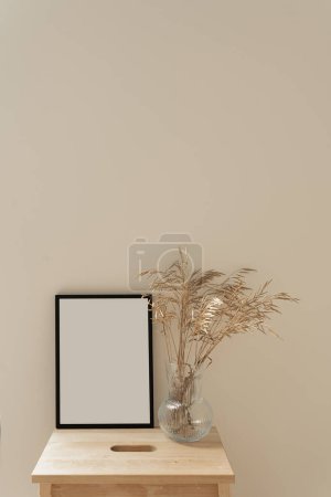 Téléchargez les photos : Cadre photo vierge avec espace de copie vide et bouquet d'herbe séchée sur fond neutre - en image libre de droit