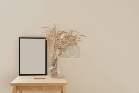 Foto de Marco de fotos en blanco con espacio de copia vacío y ramo de hierba seca sobre fondo neutro - Imagen libre de derechos