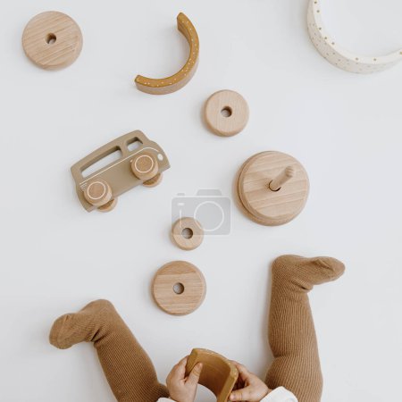 Téléchargez les photos : Enfant jouant avec des jouets en bois. Vue de dessus, couleurs beige neutre - en image libre de droit