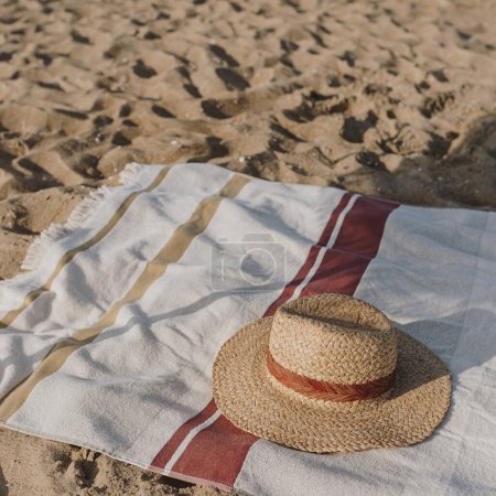 Foto de Sombrero de paja femenina y toalla de playa en arena de playa. Estilo de vida estético mínimo blog de moda, revista, medios sociales. Tomar el sol, relajarse, relajarse en las vacaciones de verano - Imagen libre de derechos