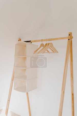 Téléchargez les photos : Cintres sur le plancher de bois cintre sur mur blanc. Concept intérieur minimal de garde-robe à la maison - en image libre de droit