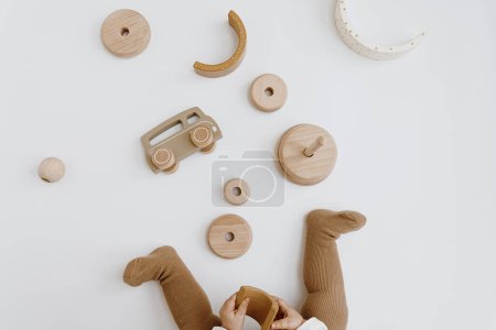 Téléchargez les photos : Enfant jouant avec des jouets en bois. Vue de dessus, couleurs beige neutre - en image libre de droit