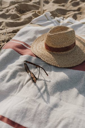 Téléchargez les photos : Chapeau de paille, lunettes de soleil, serviette de plage sur sable de plage. Minimal mode féminine fond de vogue - en image libre de droit