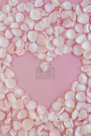 Foto de Marco floral estético mínimo. Símbolo del corazón hecho de pétalos de flor de rosa sobre fondo rosa pálido. Fondo del Día de San Valentín creativo. Copiar espacio, plano, vista superior - Imagen libre de derechos