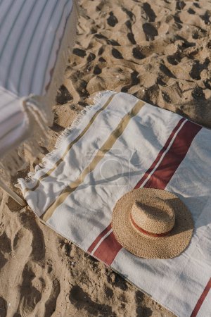 Foto de Sombrero de paja, sombrilla, toalla de playa sobre arena de playa. Fondo de moda femenina mínima moda - Imagen libre de derechos