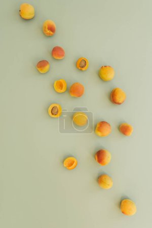 Foto de Acostado plano con melocotones maduros sobre una superficie verde pastel neutro - Imagen libre de derechos