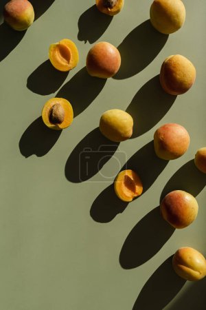 Foto de Acostado plano con melocotones maduros sobre una superficie verde claro neutro con sombras - Imagen libre de derechos