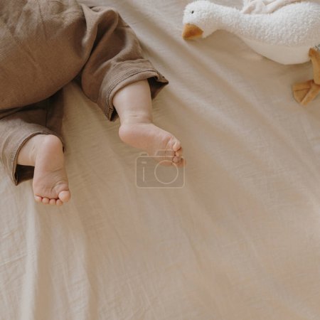 Photo for Flatlay newborn baby in cute brown bodysuit lying on bed linens - Royalty Free Image