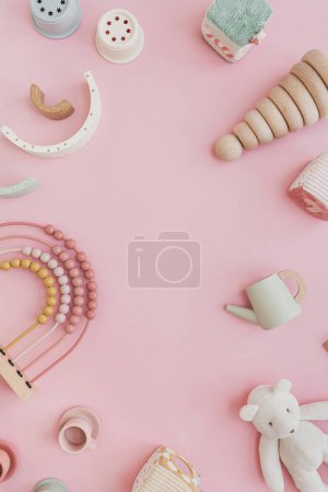 Baby toddler organic natural wooden toys on pastel pink background. Stacking cups, rainbow, kitchenware. Flat lay, top view copy space mock up
