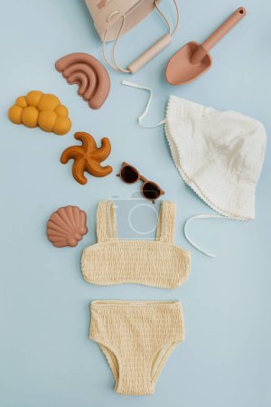 Téléchargez les photos : Bébé tout-petit enfant jouets de plage naturels biologiques, vêtements de mode et accessoires sur fond bleu pastel. Couché plat, vue du dessus - en image libre de droit