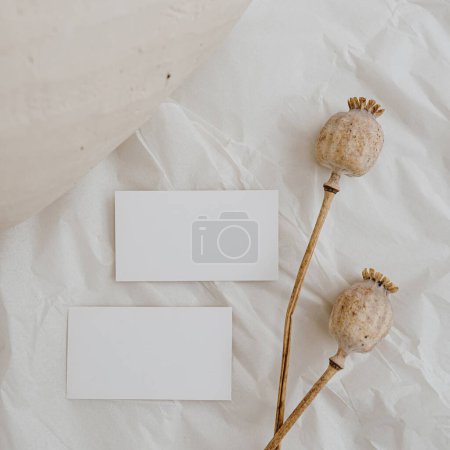 Photo for Blank paper card sheet with empty free copy space for mock up. Poppy stems and clay pot. Aesthetic neutral beige colour. Flat lay, top view - Royalty Free Image