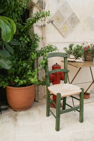 Téléchargez les photos : Vieux pot médiéval en argile avec lierre, chaise sur mur de pierre. Architecture traditionnelle européenne, grecque. Voyage d'été - en image libre de droit
