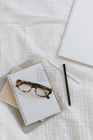 Foto de Hojas de cuaderno, bolígrafo, gafas sobre fondo blanco. Trabajo en casa plano laico, vista superior espacio de copia en blanco concepto - Imagen libre de derechos