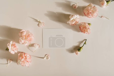 Photo for Blank paper sheet card with mockup copy space and carnation flowers on white background. Aesthetic sunlight shadows. Minimal business brand template - Royalty Free Image