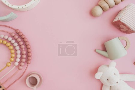 Baby toddler organic natural wooden toys on pastel pink background. Stacking cups, rainbow, kitchenware. Flat lay, top view copy space mock up