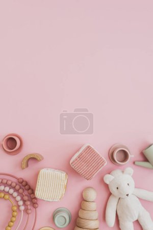 Set of stylish natural Scandinavian baby kids toys on pastel pink background with blank copy space for mock up. Baby girl stuff for playing and education. Flat lay, top view