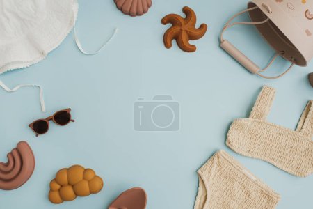 Téléchargez les photos : Ensemble de jouets et vêtements de plage scandinaves nordiques pour bébés sur fond bleu pastel avec espace de copie vierge pour se maquiller. Bébé fille trucs pour jouer sur la plage. Couché plat, vue du dessus - en image libre de droit