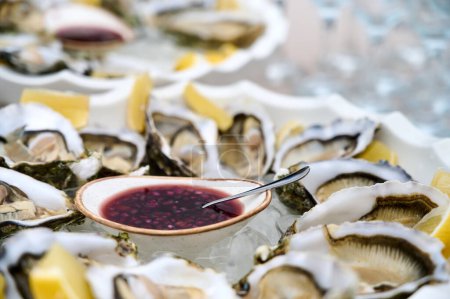 huîtres fraîches ouvertes dans deux assiettes avec tranches de citron et sauce rouge dans un bol. Gros plan. 