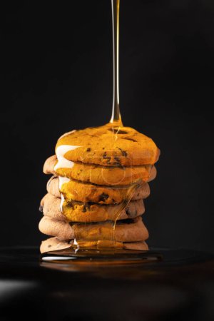 Photo for Cookies with honey on a black background. Homemade cookies and honey. Honey pours on cookies side view. Sweet breakfast. Dessert. - Royalty Free Image