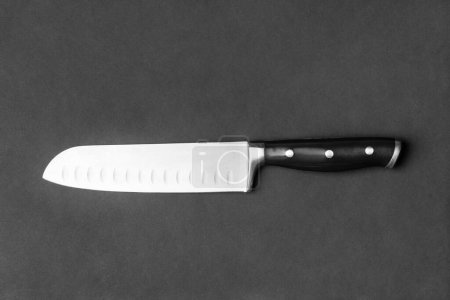 Kitchen knife with a black handle on a black background. Large knife on a dark background top view. Kitchenware. Knife with a wide blade.
