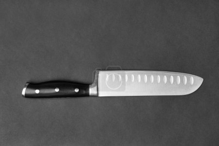Foto de Kitchen knife with a black handle on a black background. Large knife on a dark background top view. Kitchenware. Knife with a wide blade. - Imagen libre de derechos