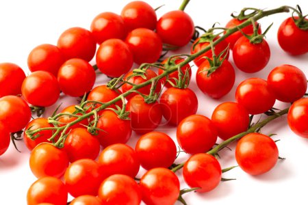 Téléchargez les photos : Beautiful long branches of fresh ripe cherry tomatoes on a white background close-up top view. Organic vegetables. Cherry tomatoes isolated. - en image libre de droit
