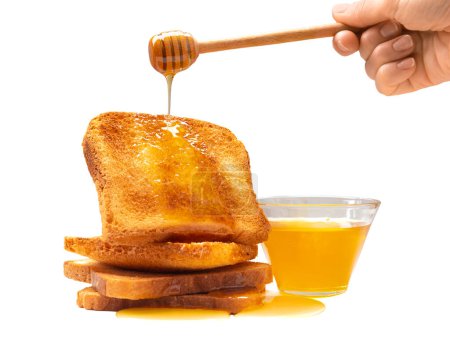 Photo for Honey pours from a wooden dipper onto toast bread and a bowl of honey on a white background. Honey stick in hand, toasts and pouring honey on isolation. - Royalty Free Image