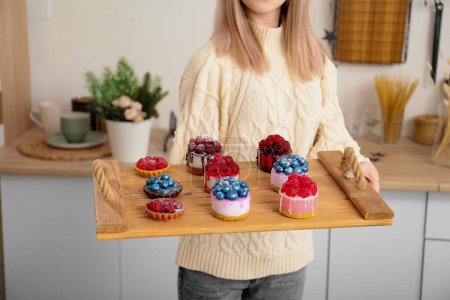 Téléchargez les photos : Handmade soap. Home made soap look like cake with berries on light background. Natural homemade cosmetics and handmade soaps concept. The girl is holding a homemade muffin in her hands - en image libre de droit