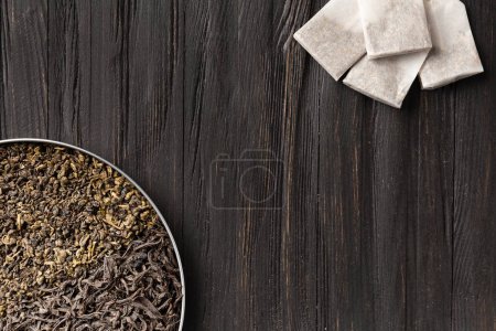 Photo for Composition of dry leaves of green, black tea and tea bags on a dark background top view copy space. Different types of tea on a wooden background with space for text. - Royalty Free Image