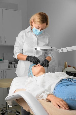 Photo for Beauty treatments by a beautician close up. The concept of improving the appearance. Lip augmentation, symmetry, plump lips. New techniques in cosmetology. Gloved hands. Syringe in hand. - Royalty Free Image