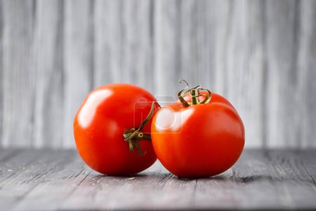 Téléchargez les photos : Two large fresh ripe tomato with a green tails on a light wooden background close-up. Organic vegetarian product for a healthy diet. - en image libre de droit