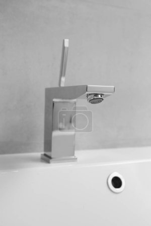 Foto de Grifo de cromo moderno en un lavabo blanco en el baño de cerca. Cuarto de baño plomería. - Imagen libre de derechos