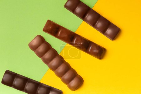 Photo for Whole bars of dark and milk chocolate on a bright yellow, green background top view. Chocolate on contrasting backgrounds. - Royalty Free Image
