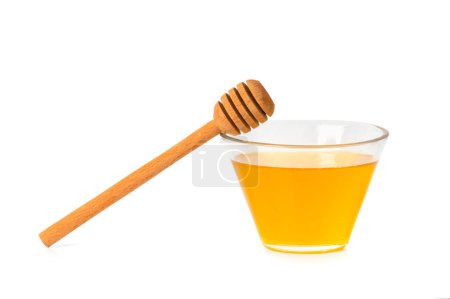 Téléchargez les photos : Fresh honey in a glass transparent bowl with a wooden dipper on a white isolated background. Honey in an open glass jar with a honey stick. Honey on a white background. - en image libre de droit