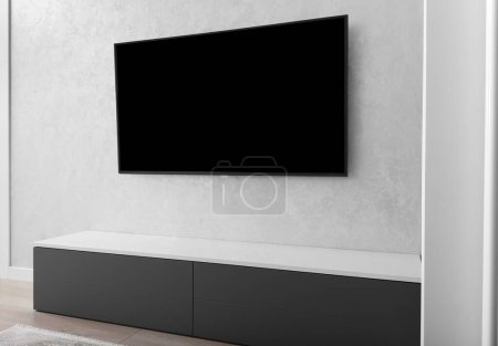 Part of the interior of a modern living room, a smart LED TV on a gray wall, a gray cabinet, a carpet. Minimalism in the interior. Light tones living rooms.