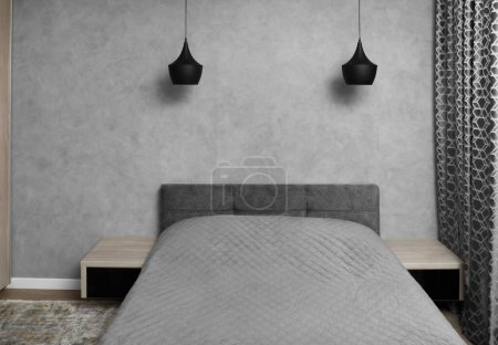 Photo pour Design moderne de la chambre dans des tons gris, minimalisme à l'intérieur. Un grand lit dans la chambre, tables de chevet avec verre noir, lustres noirs, tapis. - image libre de droit