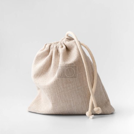 Photo for Tied small bag made of natural fabric on a white background. Cotton bag with drawstrings on insulation. Pouch in coarse fabric with drawstrings. Closed fabric bag. - Royalty Free Image