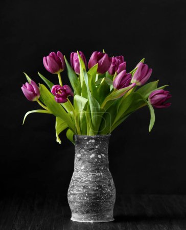 Photo for Purple tulips in a handmade vase on a dark background. Lots of beautiful purple tulips on a black background. Spring flowers in a vase. International Women's Day. March 8. - Royalty Free Image