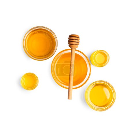 Téléchargez les photos : Composition créative de miel dans des bols en verre de différentes tailles et une trempette en bois sur fond blanc vue de dessus. Miel biologique et cuillère à miel sur l'isolement. - en image libre de droit