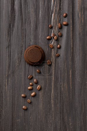 Téléchargez les photos : Waste coffee from a coffee machine and whole roasted coffee beans on a black wooden background top view. Used pressed coffee. - en image libre de droit