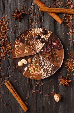 Photo for Creative composition chocolate pizza and ingredients on a dark background top view, pizza shaped chocolate with candied fruits, nuts, dry berries, chocolate on a wooden background. - Royalty Free Image