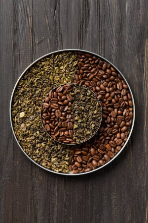 Téléchargez les photos : Thé vert sec et grains de café dans deux assiettes rondes de différentes tailles l'une sur l'autre sur un fond en bois foncé vue de dessus copier l'espace. Composition conceptuelle du thé vert et des grains de café. - en image libre de droit