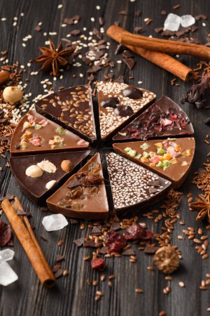 Photo for Creative composition chocolate in the shape of a pizza with candied fruits, nuts, dry berries, chocolate pizza and ingredients on a dark wooden background. - Royalty Free Image