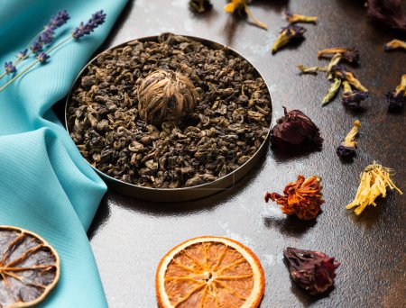 Photo for Composition of green, flower tea and dried orange slices on blue and brown backgrounds top view. Large-leaf tea, dried flowers and citrus chips on contrasting backgrounds. - Royalty Free Image