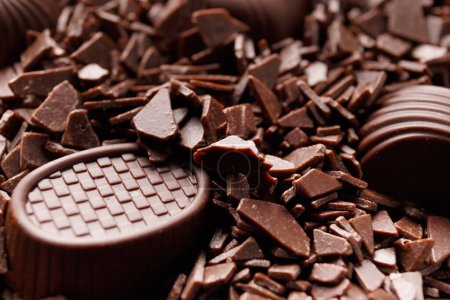 Téléchargez les photos : Magnifiques bonbons au chocolat noir trempés dans des pépites de chocolat gros plan, concept de fabrication de bonbons au chocolat, fond de chocolat. - en image libre de droit