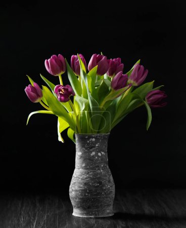 Téléchargez les photos : Tulipes violettes dans un vase fait à la main sur un fond sombre. Beaucoup de belles tulipes violettes sur fond noir. Fleurs printanières dans un vase. Journée internationale de la femme. 8 mars. - en image libre de droit