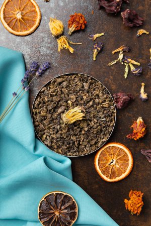 Photo for Composition of green, flower tea and dried orange slices on blue and brown backgrounds top view. Large-leaf tea, dried flowers and citrus chips on contrasting backgrounds. - Royalty Free Image