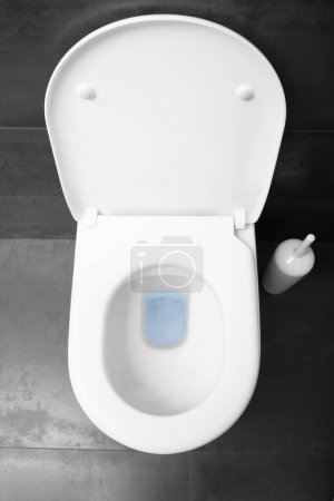 Téléchargez les photos : Vue de dessus d'un cuvette de toilette blanche avec couvercle surélevé contre un sol en céramique noire. - en image libre de droit