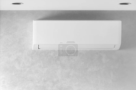 Téléchargez les photos : Climatiseur blanc sur un mur gris dans une maison, appartement, espace de copie. Système de climatisation. L'unité intérieure d'un système de séparation pour le refroidissement et le chauffage de la pièce. Climatiseur mural. - en image libre de droit