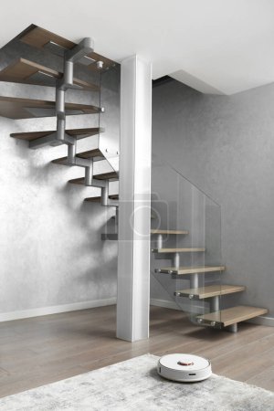 Photo for A staircase with wooden steps and an elegant glass fence, a column of matte glass, large indoor flower in the modern interior of the apartment. Stairs design in a two -level apartment. - Royalty Free Image